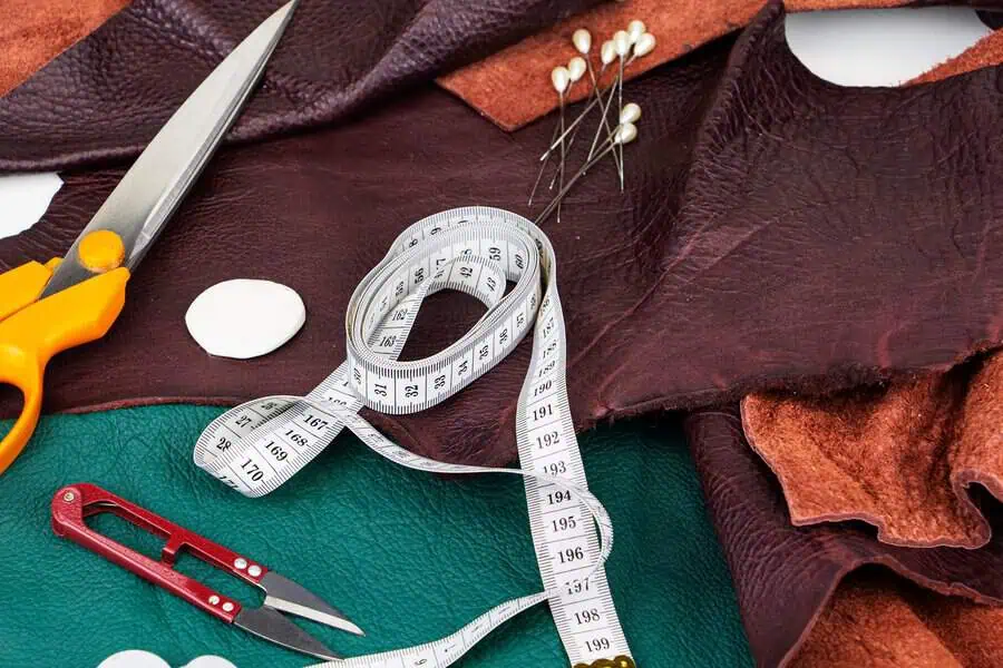 Leather fabric and upholstery tools including scissors, measuring tape, and sewing pins.