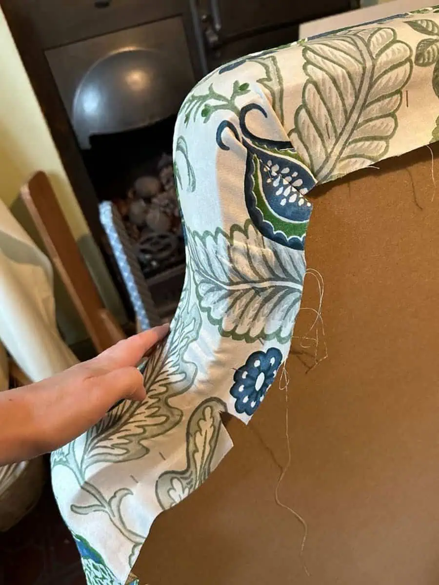 Applying floral fabric to the back of a chair during a reupholstery project.