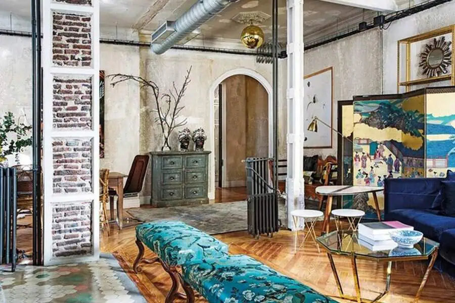 Eclectic interior with exposed brick, vintage furniture, blue accents, and Asian-inspired decor.