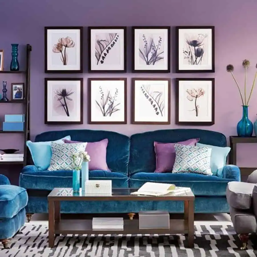 Living room with teal velvet sofas, lavender walls, floral wall art, and colorful decorative pillows.