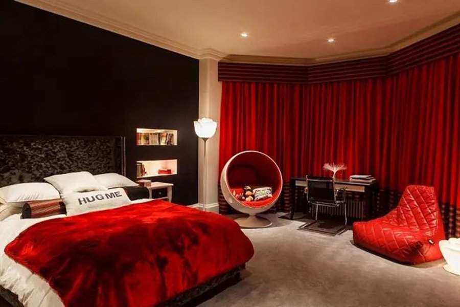 Modern bedroom with bold red accents, velvet bedding, and stylish furniture for couples.
