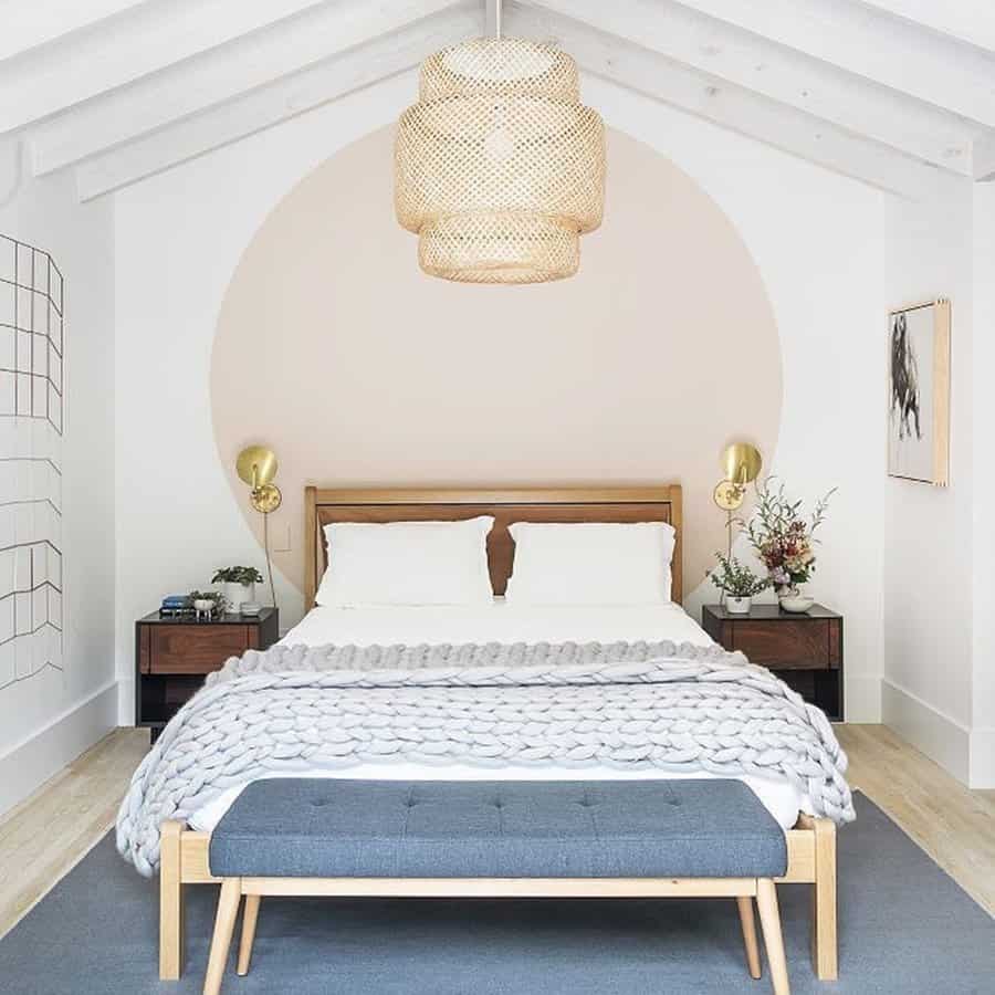 Minimalist bedroom with wooden furniture, soft pastel accents, and a woven pendant light.