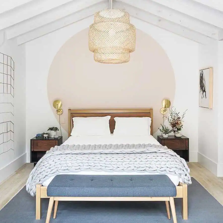 Minimalist bedroom with wooden furniture, soft pastel accents, and a woven pendant light.