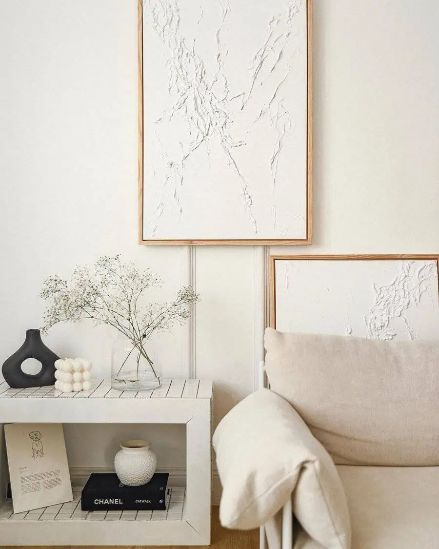 Neutral-toned living space with textured wall art, a white console table, and minimalist decor.