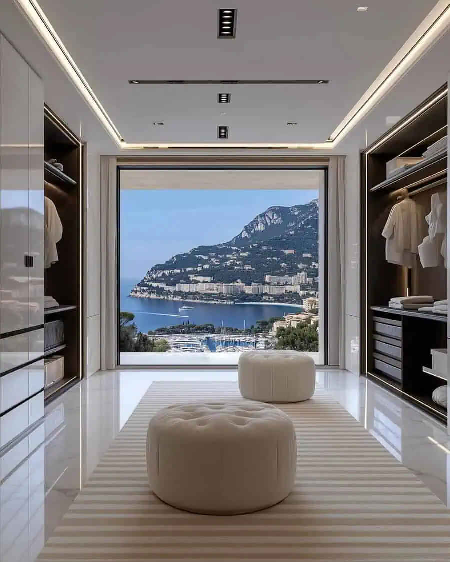 Luxurious walk-in closet with a sea view, sleek shelves, and plush white ottomans.