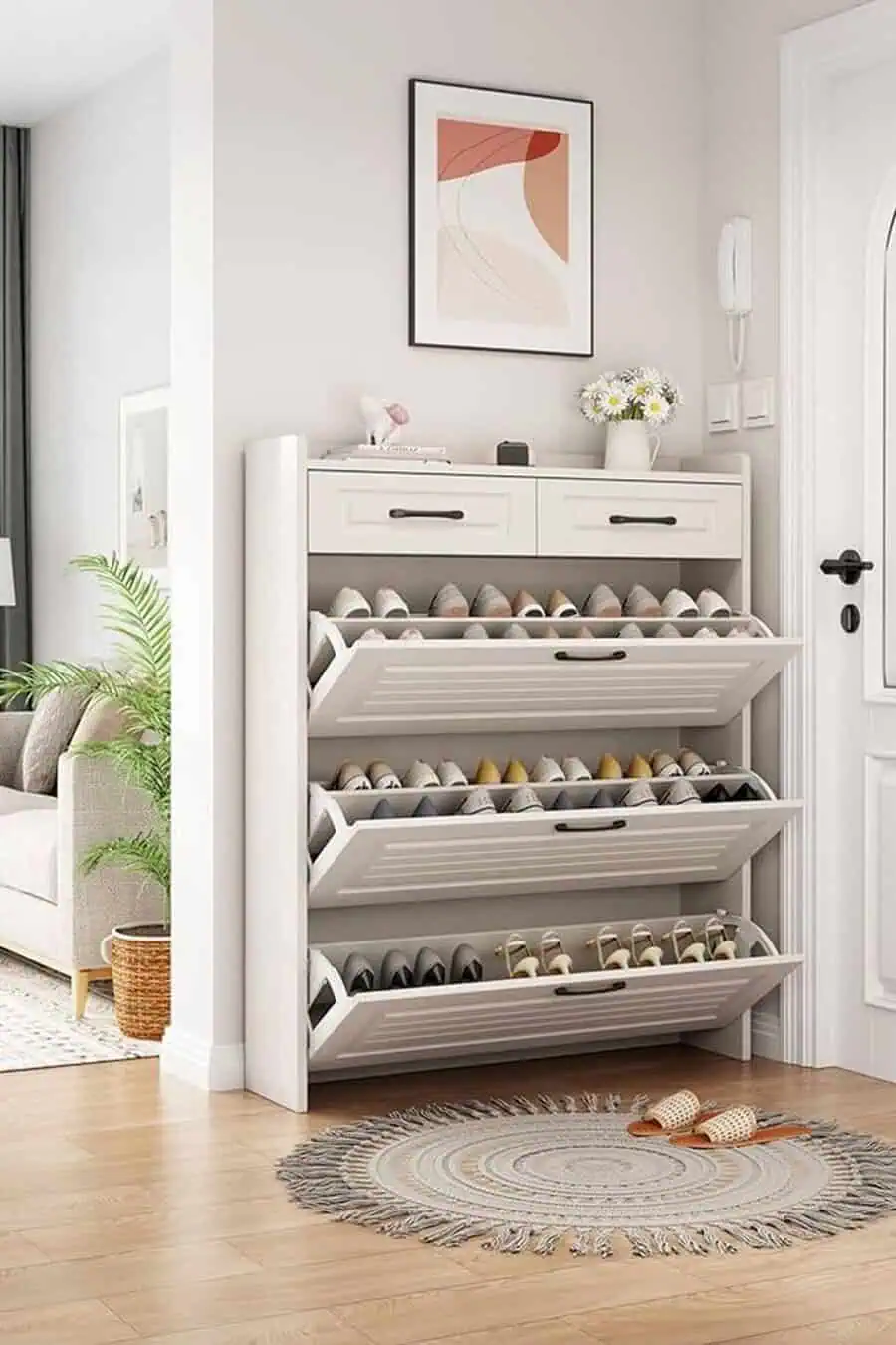 Compact shoe storage cabinet with pull-out racks, decorated with flowers and wall art.