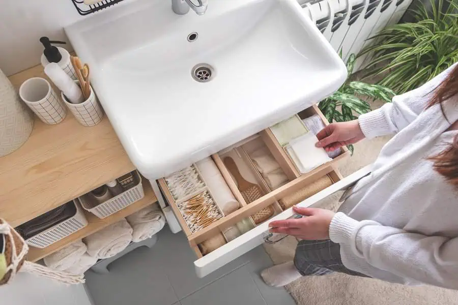 Organized bathroom drawer with neatly arranged toiletries and accessories under a sink.