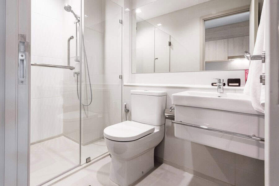 Modern bathroom with a glass shower enclosure, white fixtures, and a large mirror.