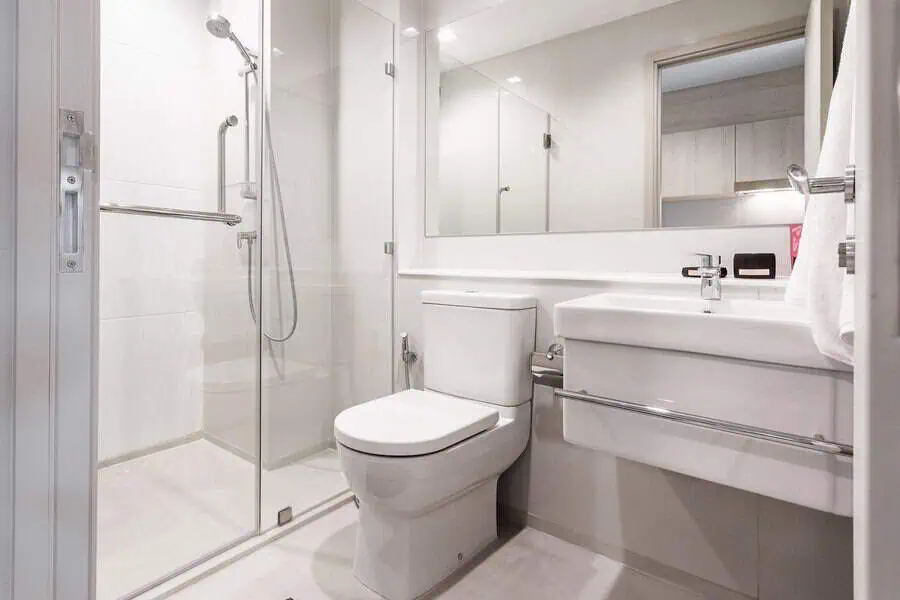 Modern bathroom with a glass shower enclosure, white fixtures, and a large mirror.