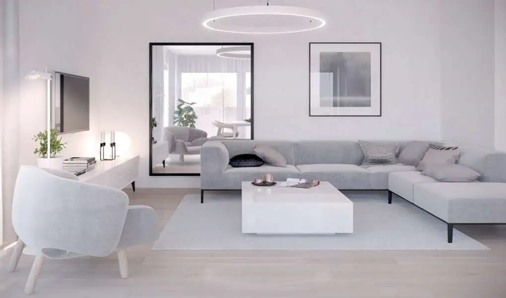 Bright living room with a grey sectional sofa, white coffee table, and a large framed mirror.