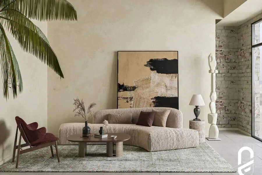 Contemporary living room with a curved beige sofa, abstract wall art, a wooden coffee table, and textured decor.