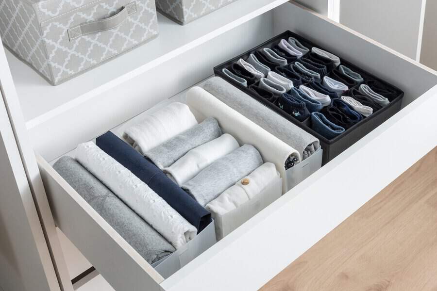 Neatly folded clothes and socks organized in a drawer with dividers.