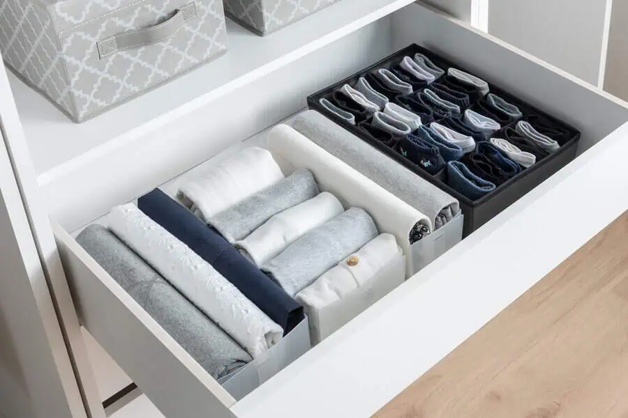 Neatly folded clothes and socks organized in a drawer with dividers.