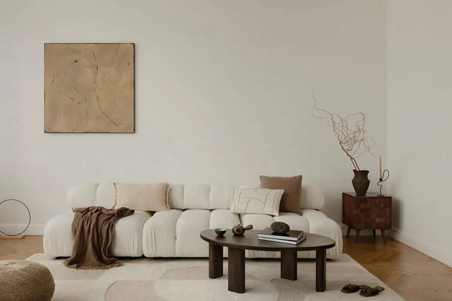 Minimalist living room with a white sofa, abstract art, and a wooden coffee table.