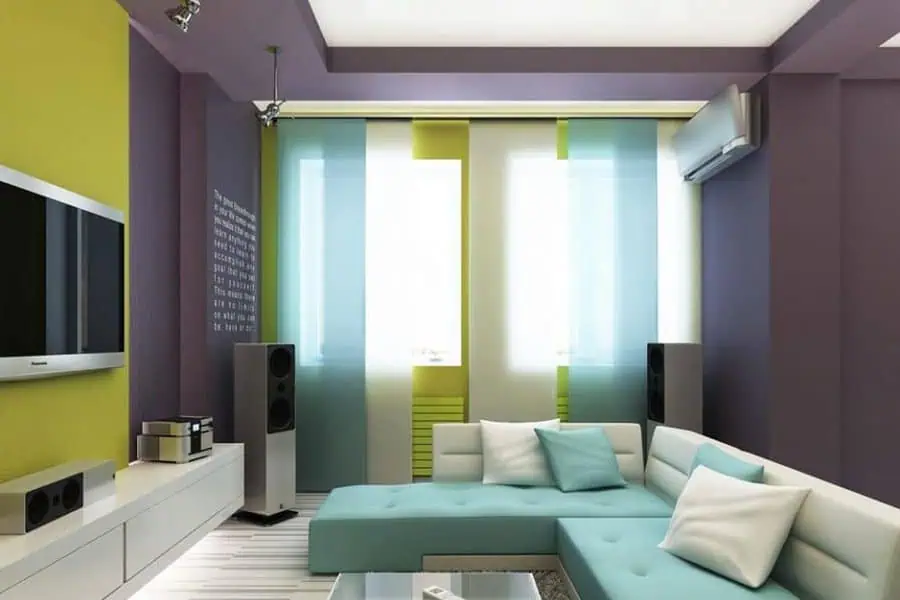 Modern living room with vibrant green and purple walls, a sectional sofa, and home entertainment setup.