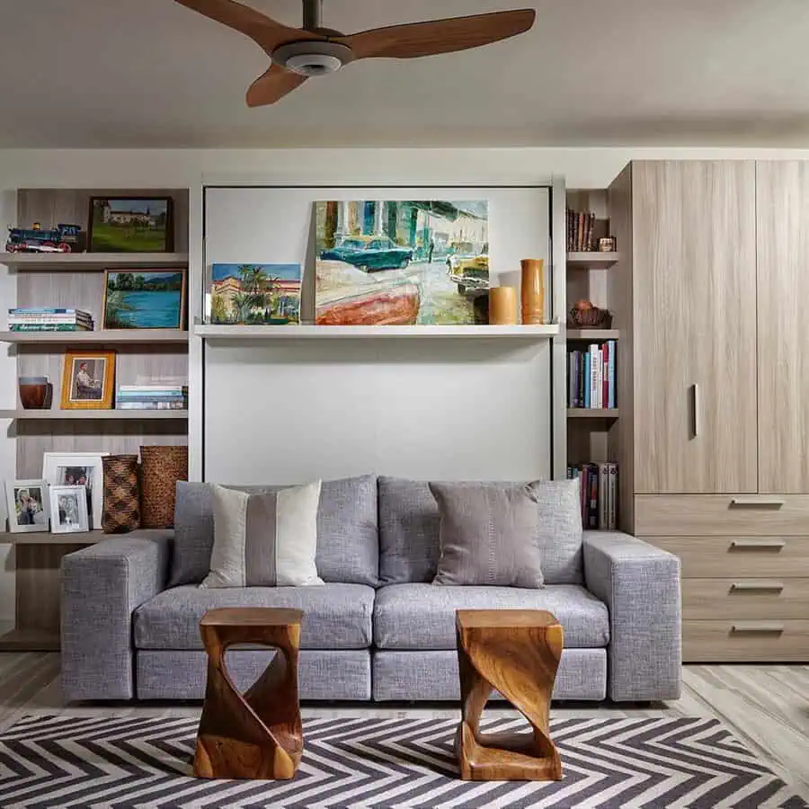 Cozy den with gray sofa, wooden furniture, bookshelf, and colorful wall art.