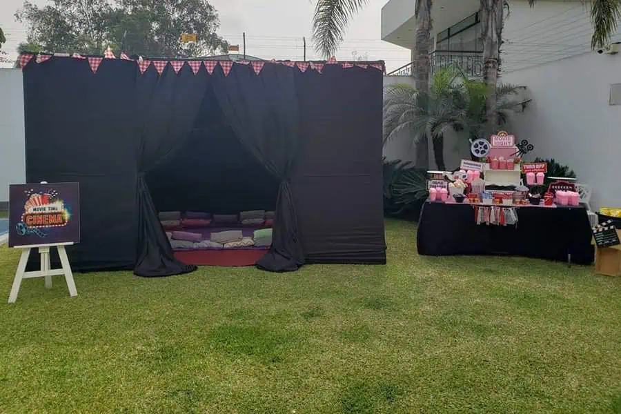 Outdoor movie-themed birthday party with a cozy tent, snacks table, and cinema decor.