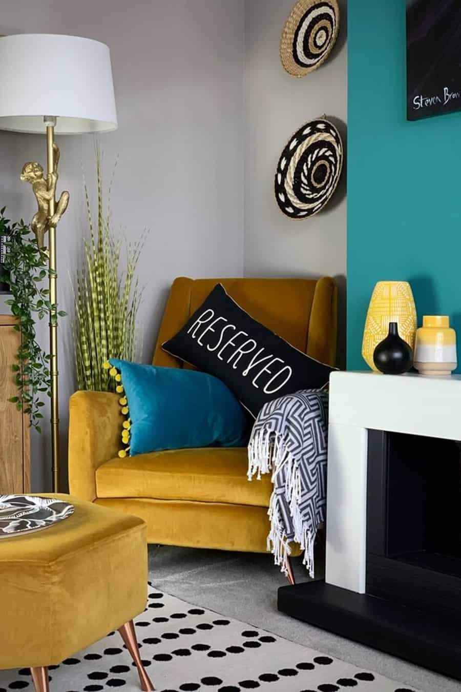 Mustard yellow armchair with teal and black pillows, next to a teal accent wall and patterned decor.