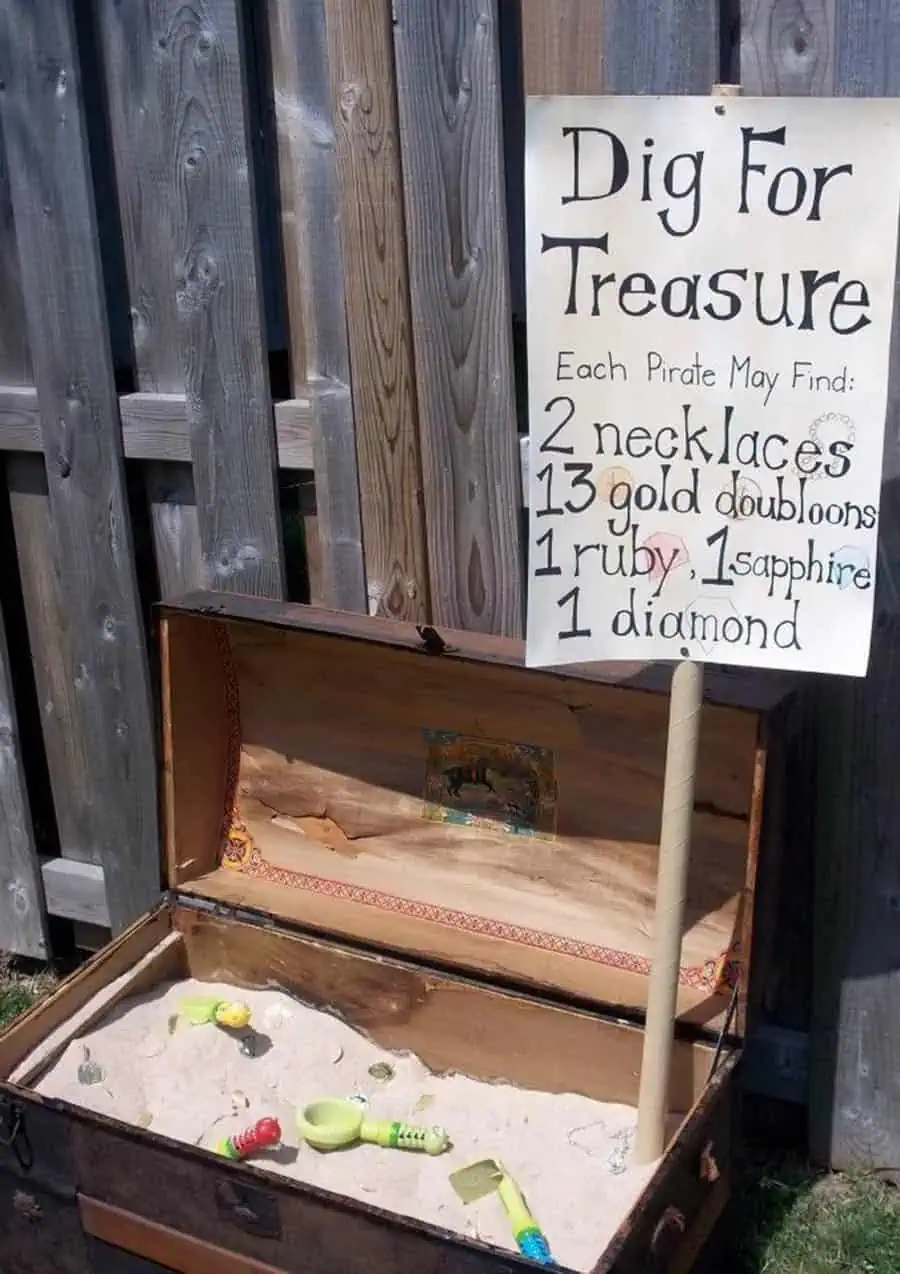 Pirate-themed outdoor birthday activity with a treasure chest and a "Dig for Treasure" sign.