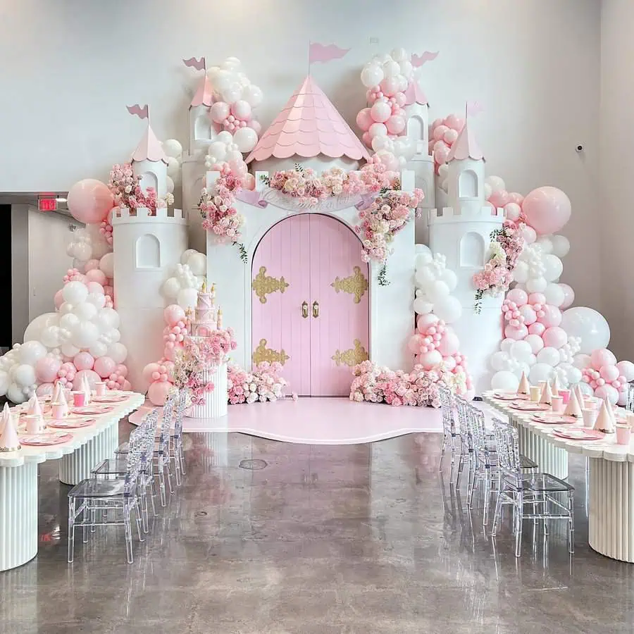 Pink princess castle birthday party setup with balloons and elegant table decor.