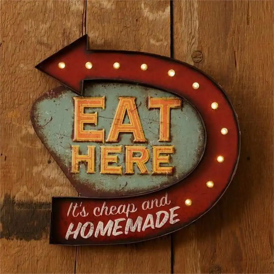 Retro "Eat Here" light-up sign with vintage design and rustic wood background.