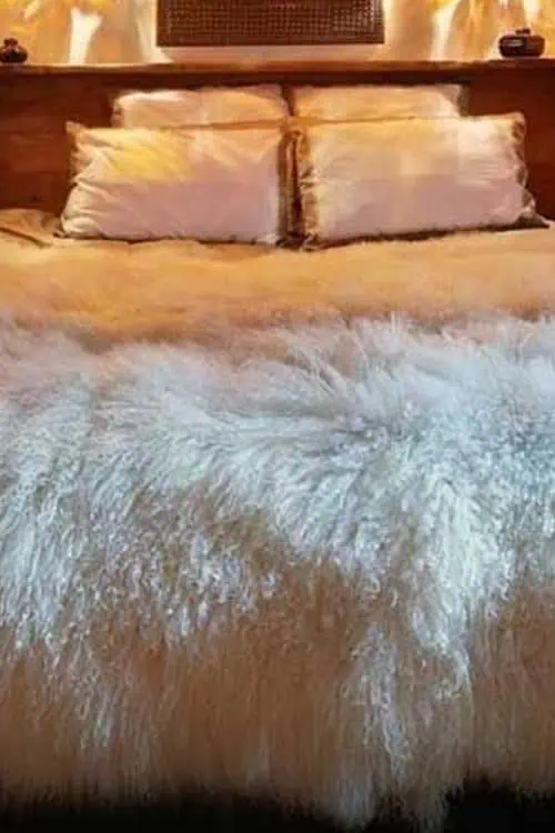 Rustic bedroom with wooden accents, warm lighting, and cozy fur bedding for couples.