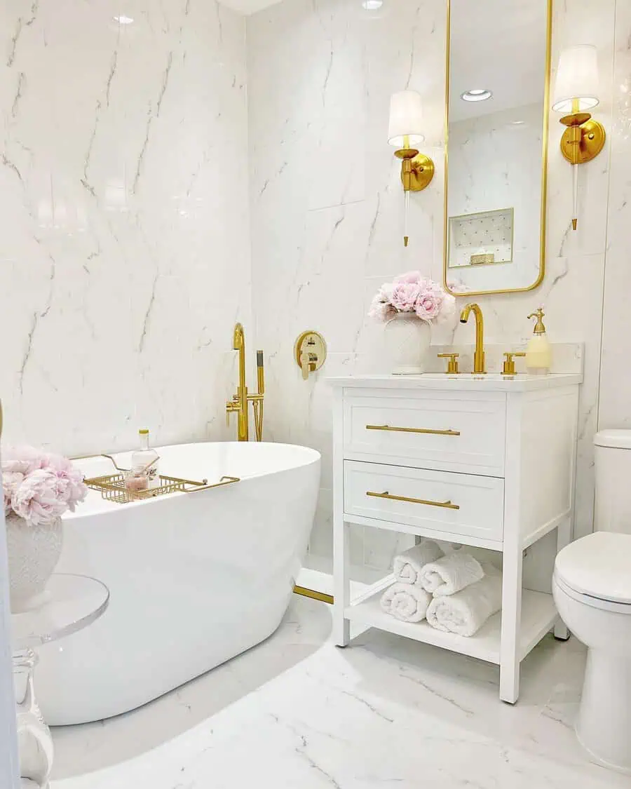 Small luxury bathroom with modern fixtures, gold accents, freestanding tub, and pink floral decor.