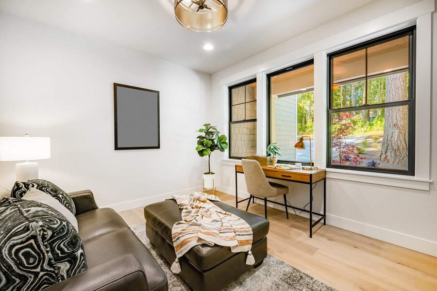 Small office space with cozy seating, work desk by large windows, and bright natural light.