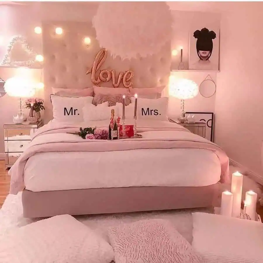 Romantic bedroom with pink tones, tufted headboard, candles, and "Mr. & Mrs." pillows.