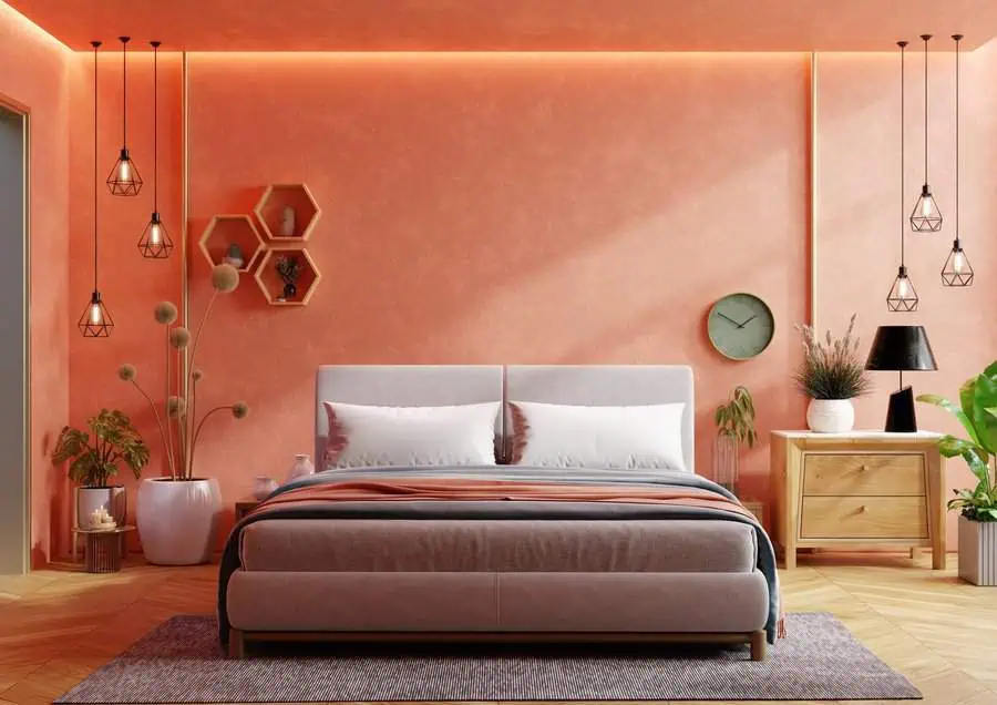 A pastel-colored bedroom with coral walls, warm lighting, and minimalistic decor accents.