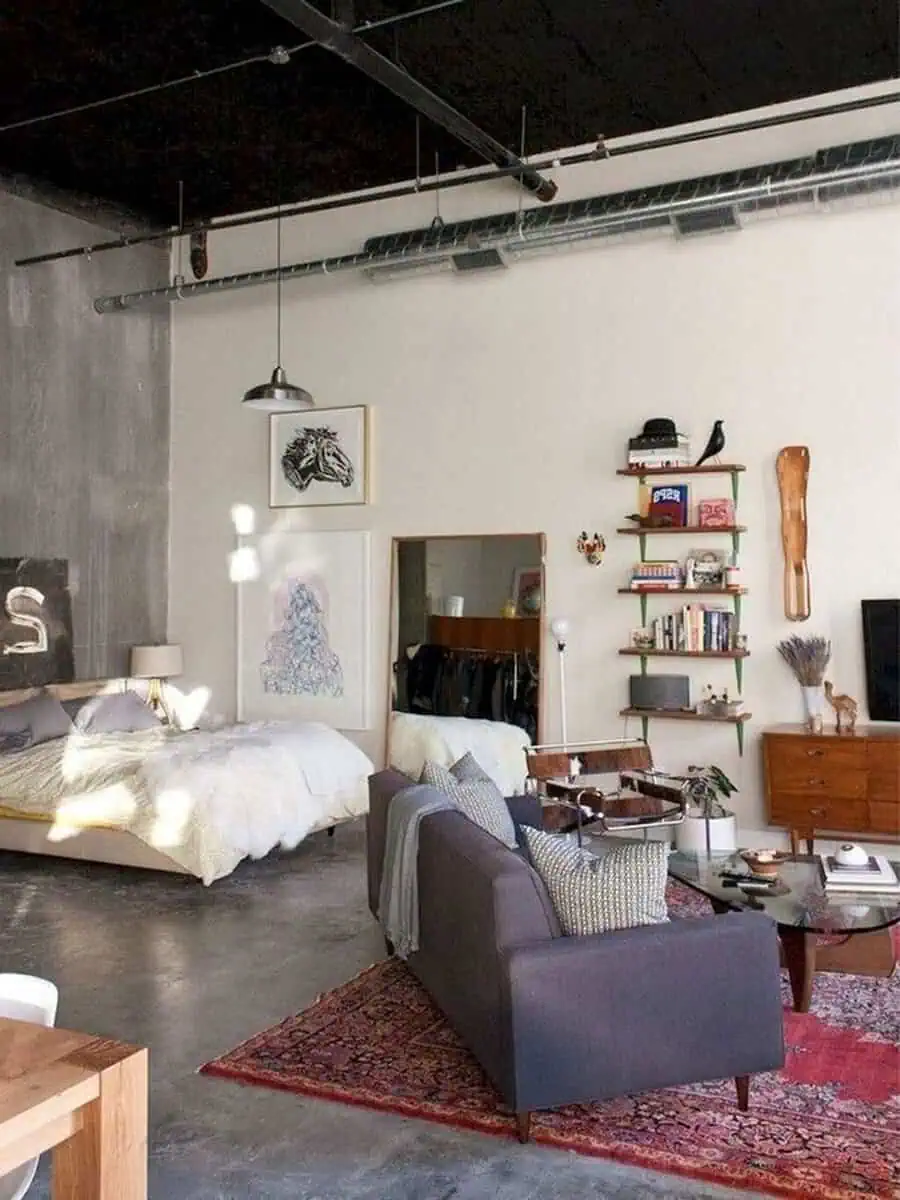 Industrial-style studio apartment with open layout, vintage rug, and compact functional furniture.