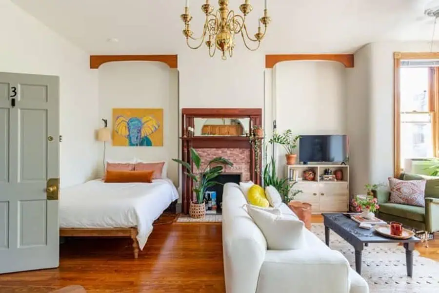 Charming studio apartment with vintage chandelier, cozy fireplace, and colorful eclectic decor.