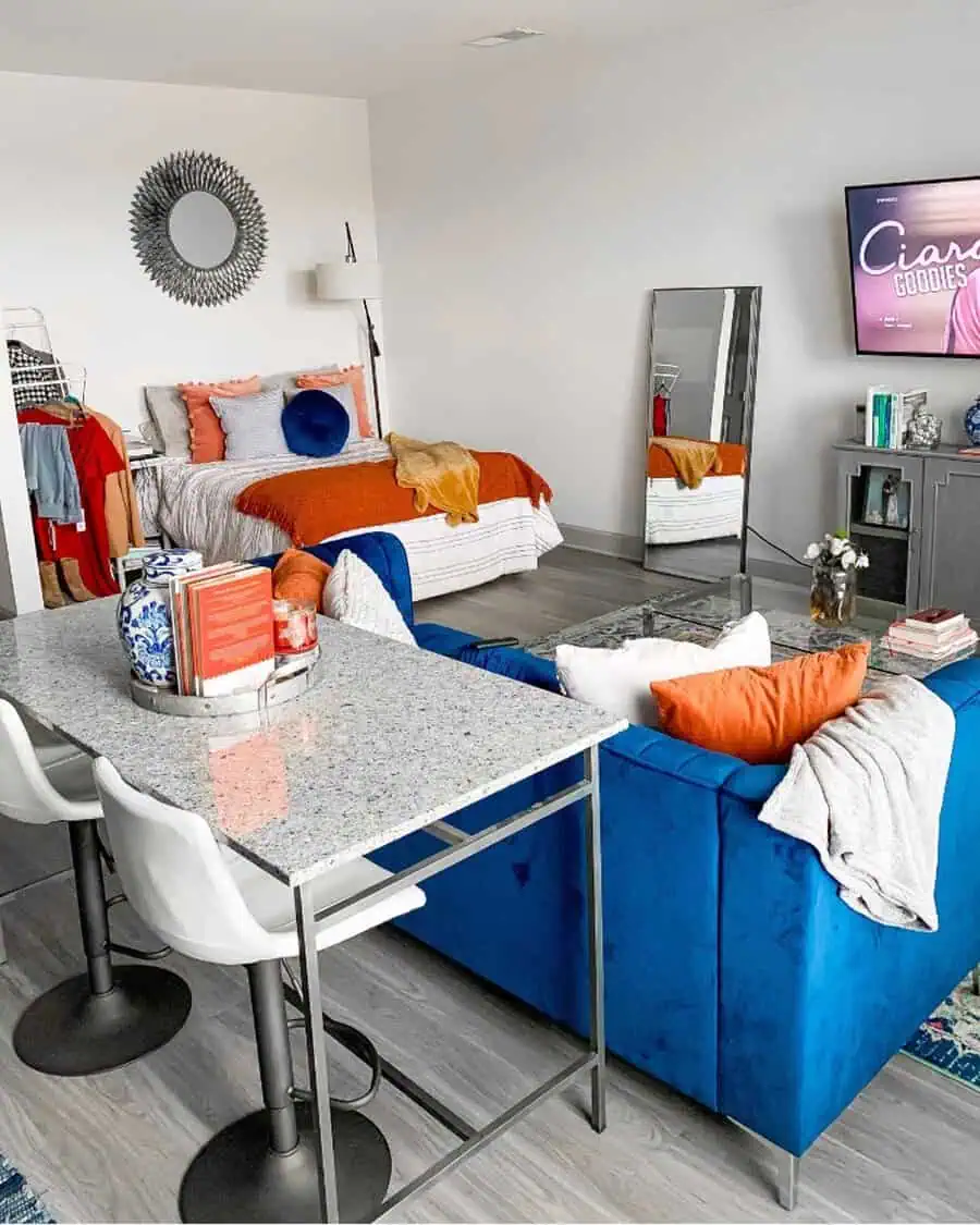 Vibrant studio apartment with bold blue sofa, colorful accents, and functional open layout.