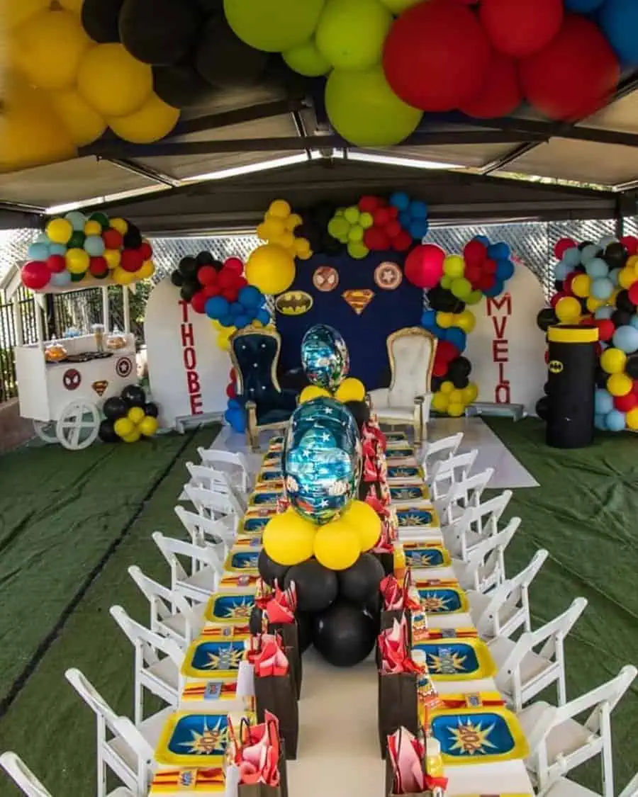 Superhero-themed birthday party with colorful balloons, themed plates, and decorative backdrop.