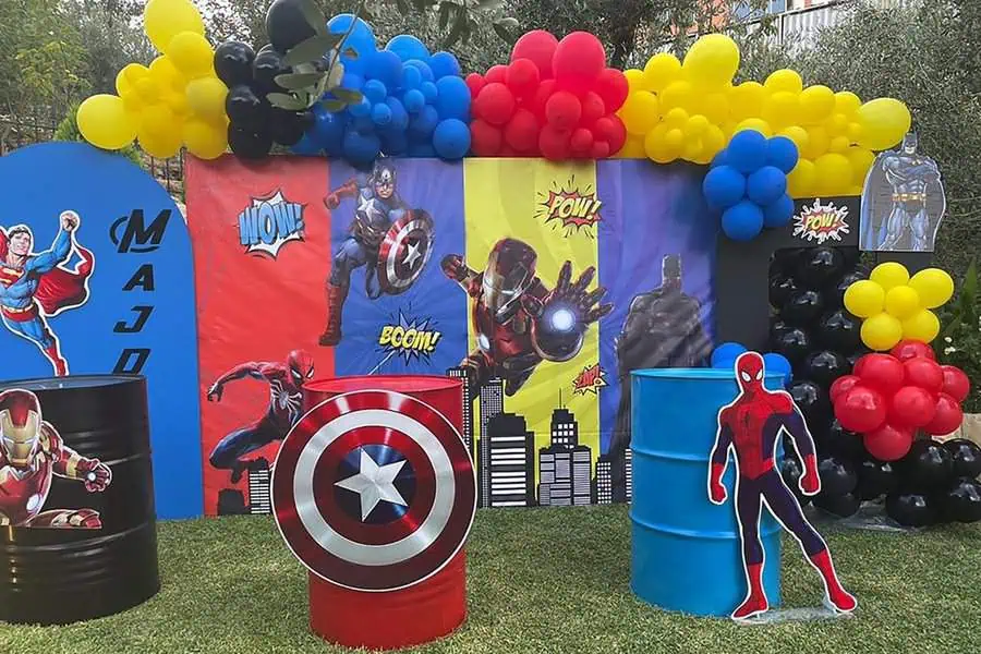 Superhero-themed birthday party backdrop with colorful balloons and character displays.