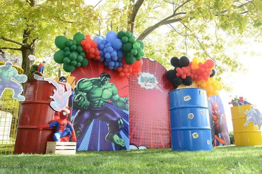 Superhero-themed outdoor birthday party with colorful balloons and character cutouts.