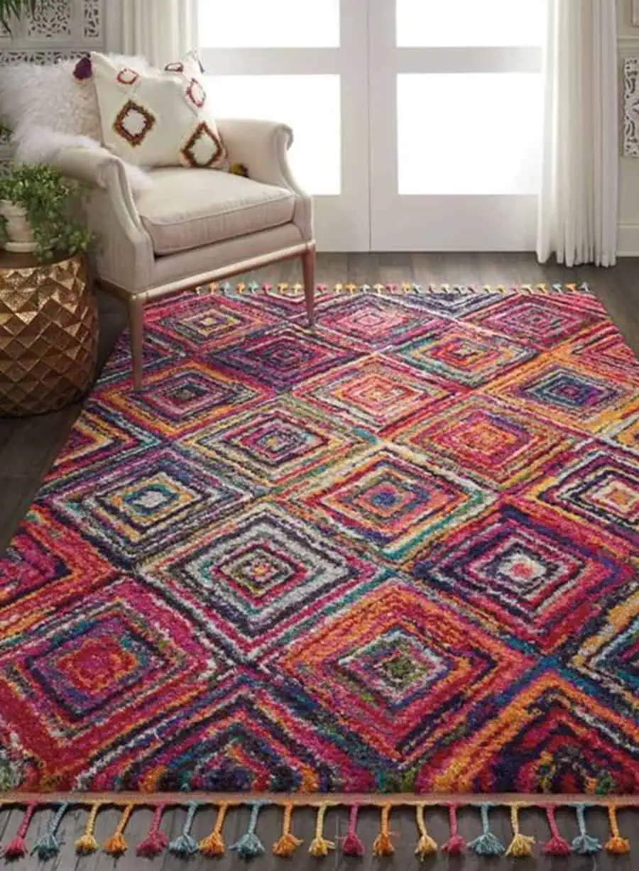 Eclectic room with a colorful geometric rug, tufted armchair, and gold accent table.