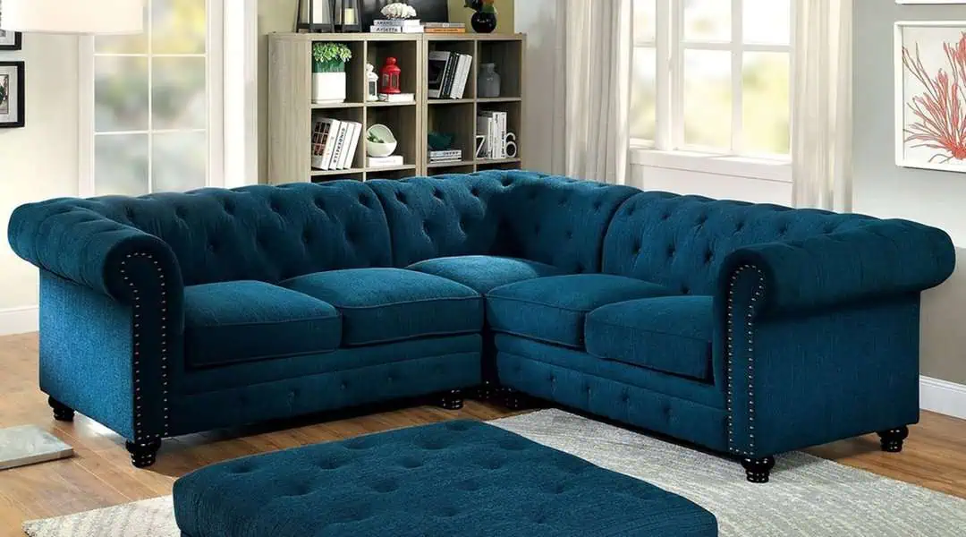 Teal Chesterfield sectional sofa with tufted design in a bright living room setting.