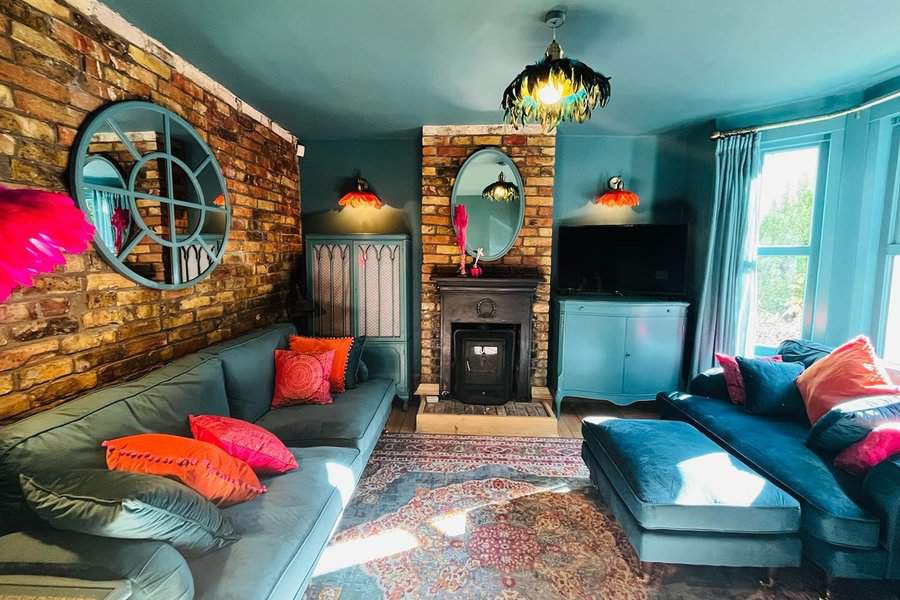 Living room with a bold teal-painted ceiling, exposed brick walls, and vibrant decor accents for a striking, eclectic style.