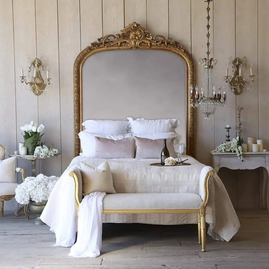 Elegant bedroom with vintage gold mirror, crystal chandelier, and neutral-toned bedding decor.