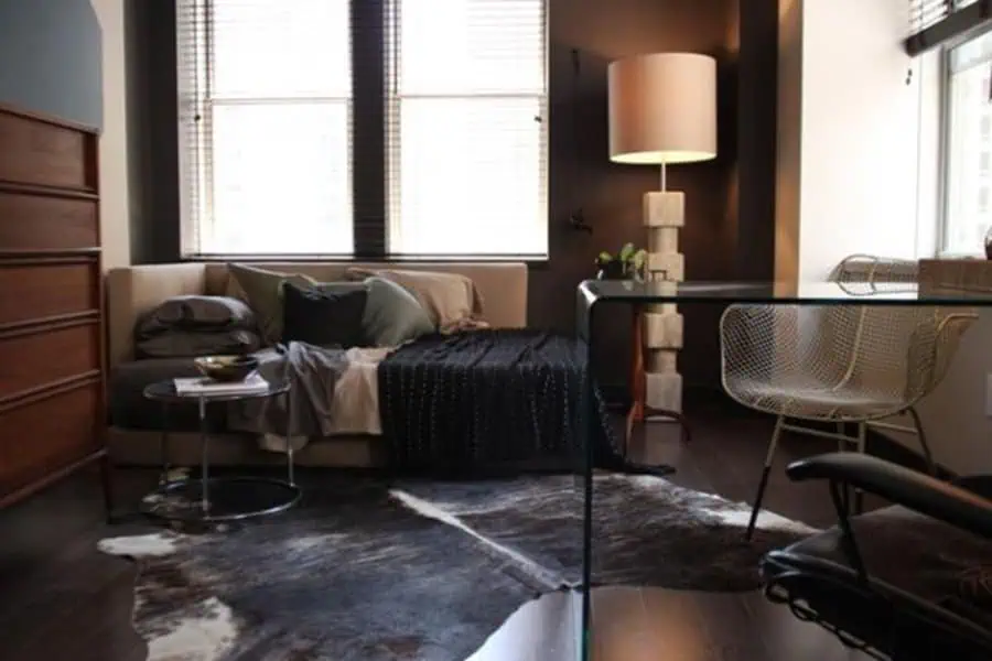 Cozy studio apartment with dark tones, a cowhide vintage rug, and modern minimalist furniture.