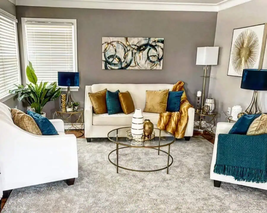 Modern living room with gray walls, white sofas, teal, warm brown, and gold accents, and abstract wall art.