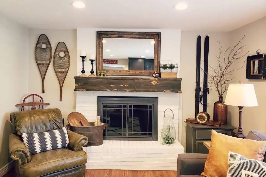 Rustic den with white brick fireplace, wooden mantle, vintage decor, and cozy seating.