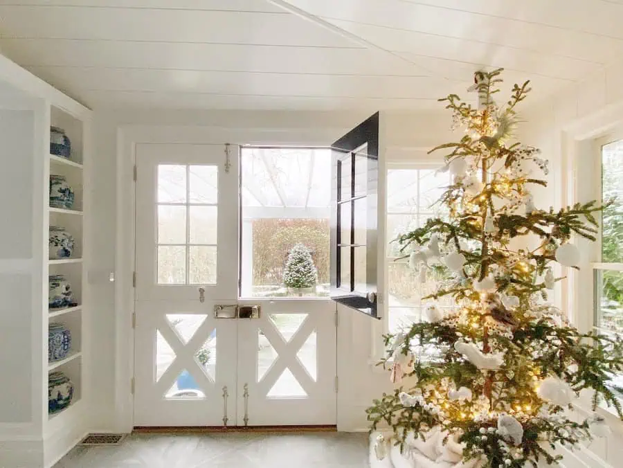 Farmhouse kitchen with wooden Dutch door, brick fireplace, and white cabinetry on hardwood floors.