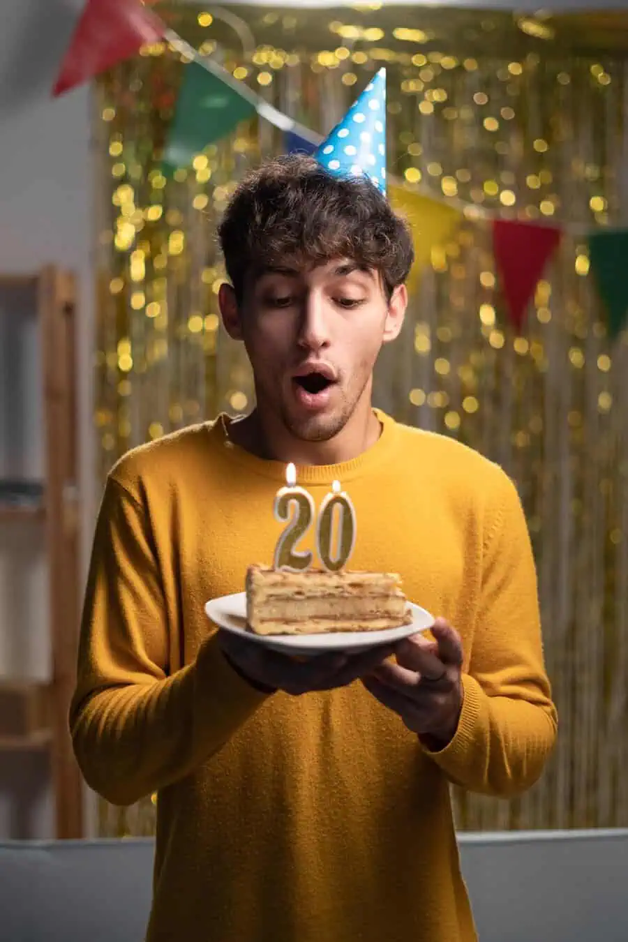 Young man celebrating 20th birthday with a cake slice and "20" candles.