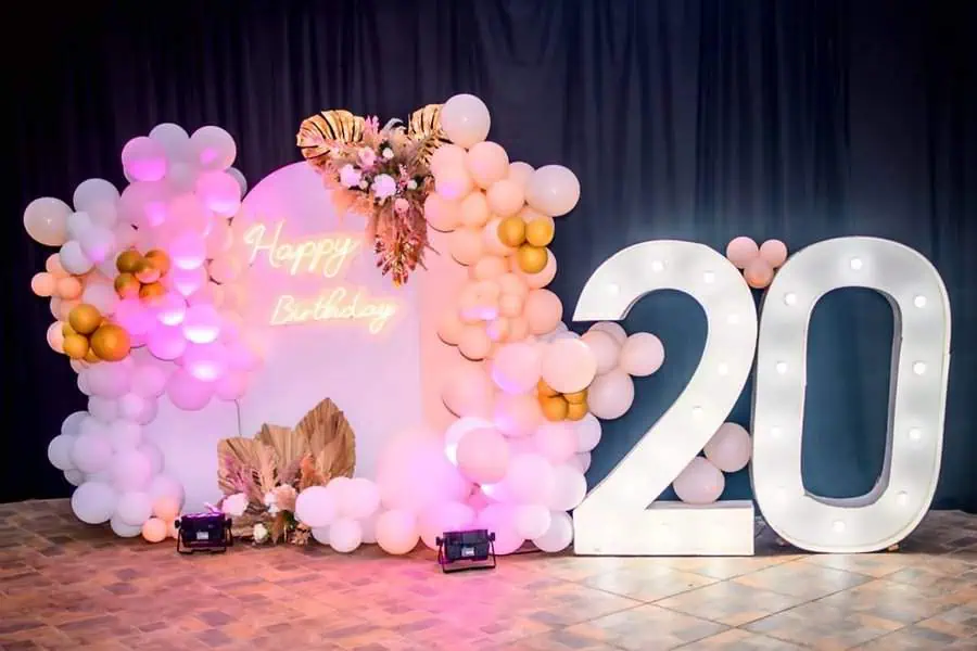 Elegant 20th birthday backdrop with balloons, neon "Happy Birthday" sign, and illuminated "20."