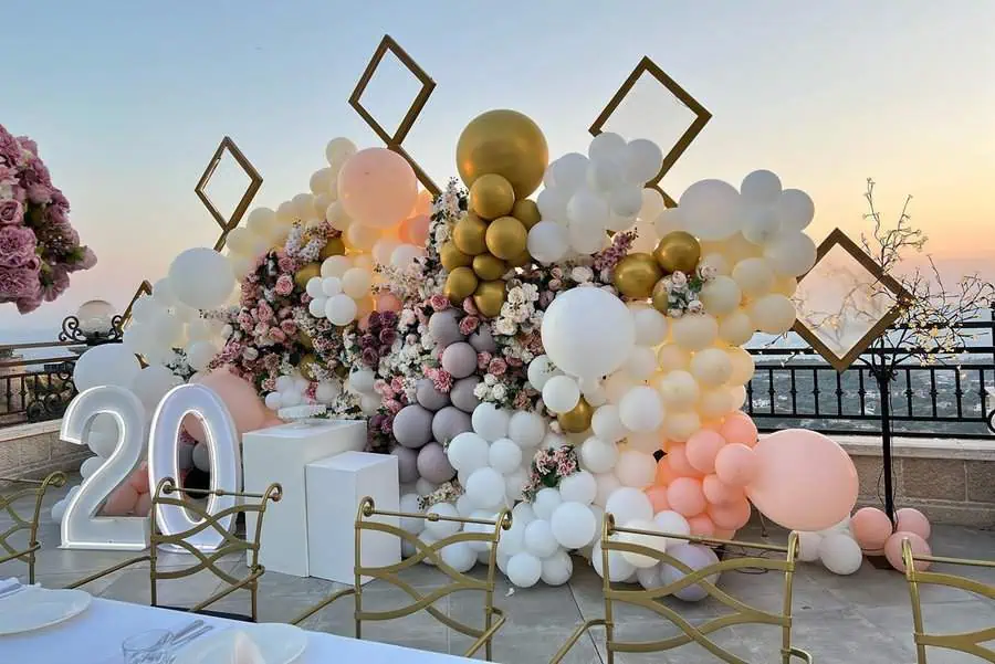 Elegant outdoor 20th birthday setup with pastel balloons, floral arrangements, and illuminated "20."