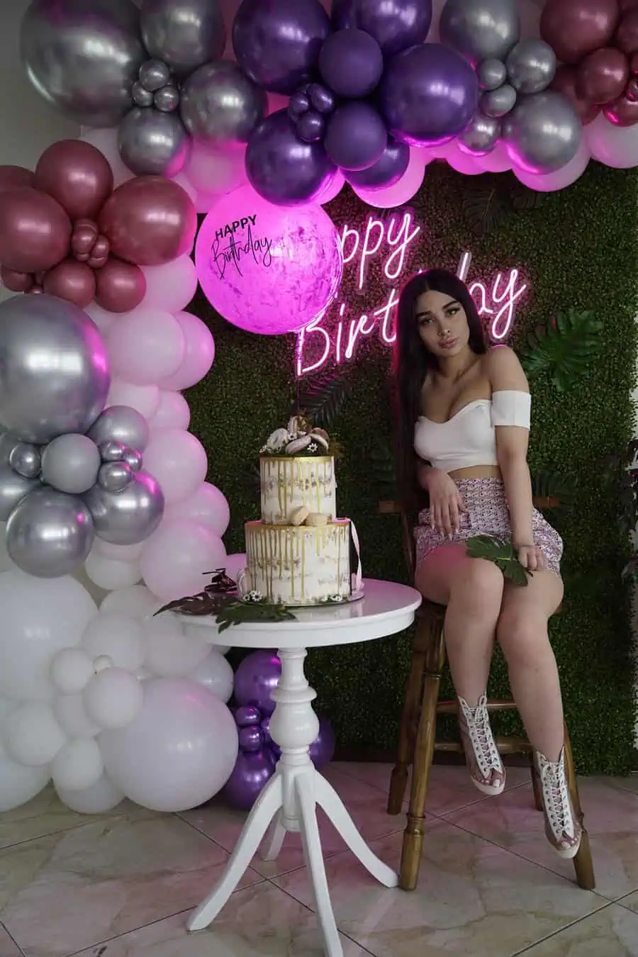 Elegant 20th birthday celebration with balloons, neon sign, and a gold-drip cake.