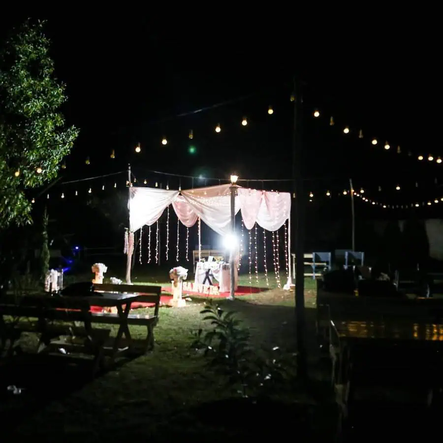 Outdoor 40th birthday celebration with string lights, draped canopy, and elegant decor.