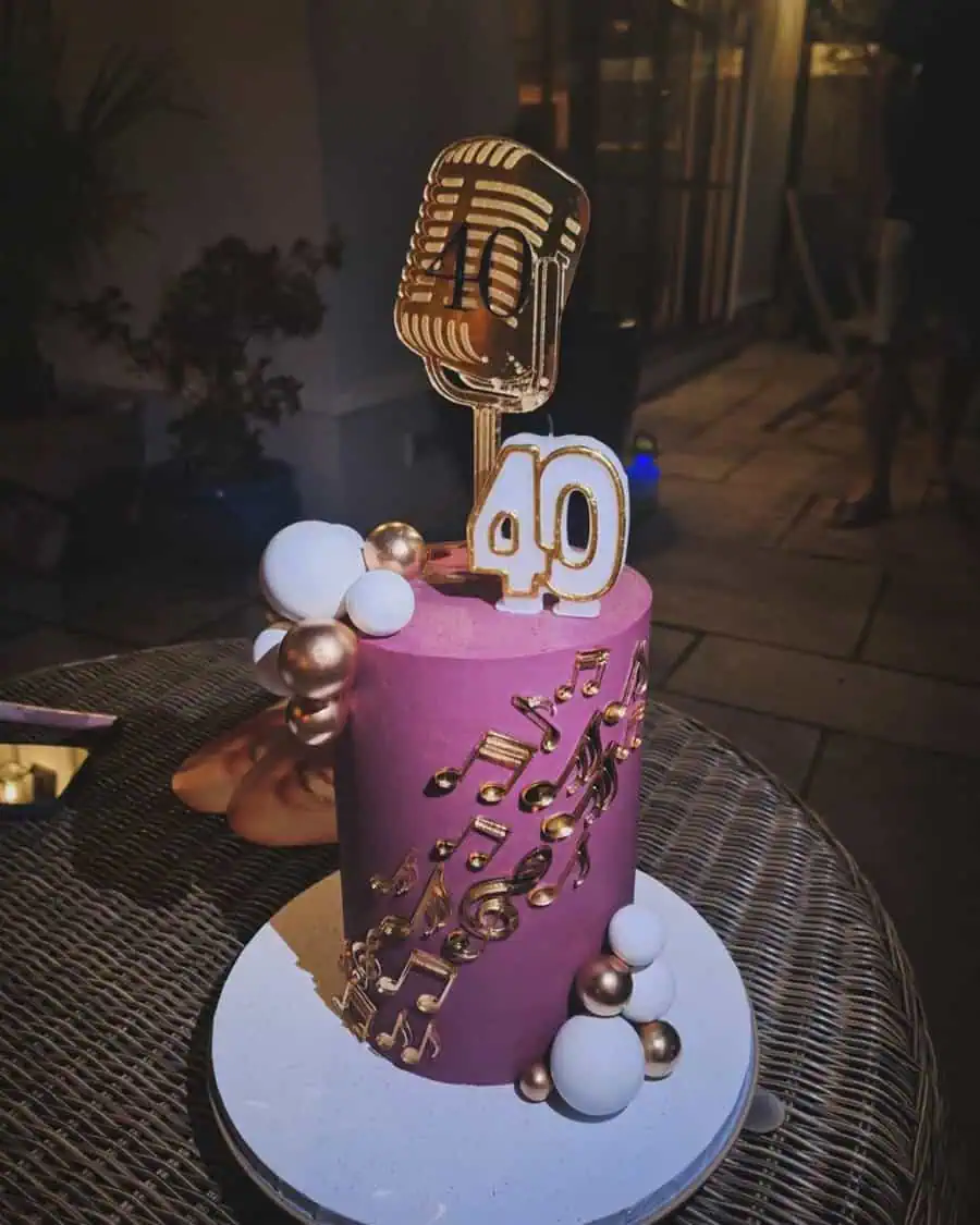 Music-themed 40th birthday cake with gold microphone topper, notes, and decorative spheres.